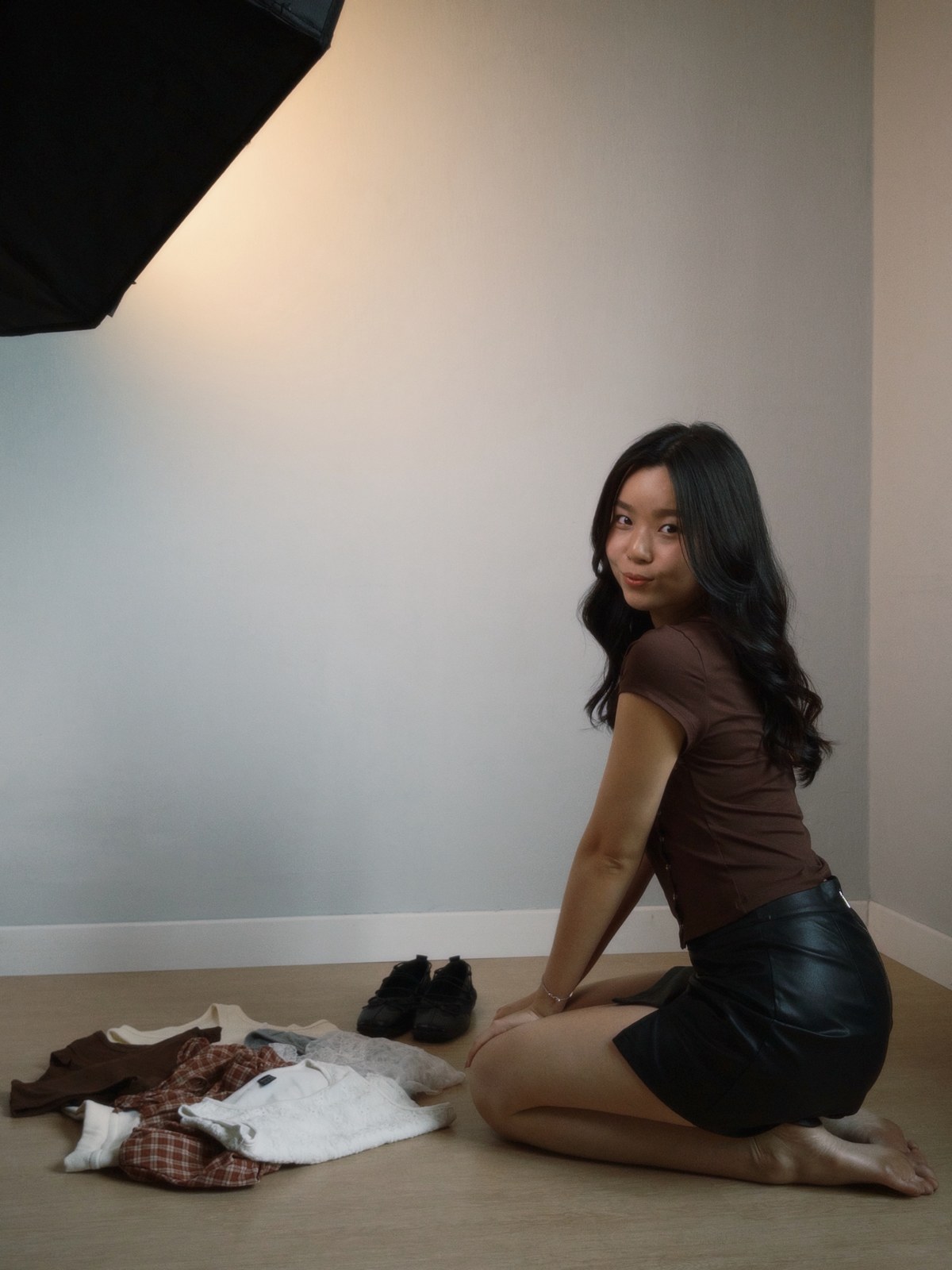 Huan Min preparing clothes for a shoot, seated beside her filming setup.